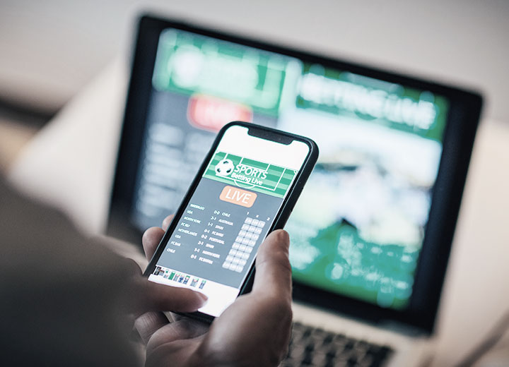 Homem usando o app móvel para apostar vivo A regulação das apostas esportivas on-line