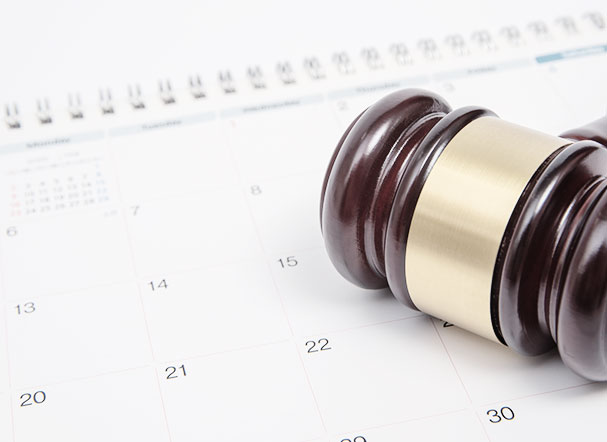 Martelo, da cor marrom, usado em sessões do tribunal, posicionado acima de um calendário