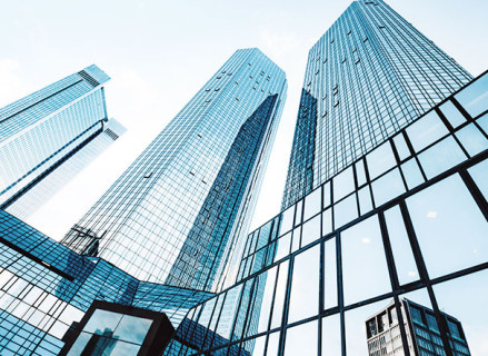 Visão inferior de vários edifícios com estrutura espelhada em azul. Os prédios tem diversos formatos de estrutura