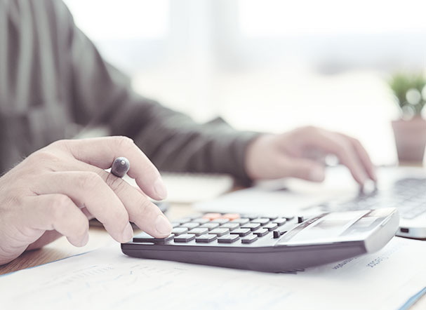 Pessoa utilizando calculadora preta com teclas em preto e vermelho
